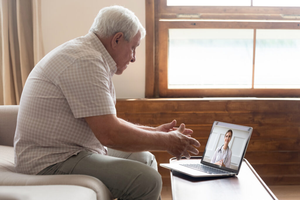 An elderly man is on a telemedicine call for his post-discharge follow-up appointment from a hospital.